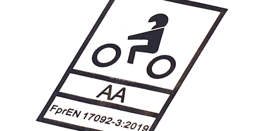 Štítek v motocyklovém oblečení: symbol jezdce, třída AA a označení normy EN 17092-3